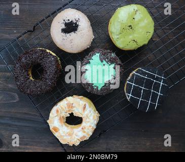 Sechs süße Donuts mit verschiedenen Belägen auf einem Holztisch Stockfoto