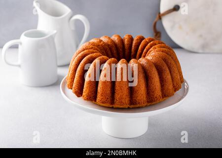 Vanille-Kuchen auf einem Kuchenständer, goldfrisch gebacken, fertig zum Essen Stockfoto