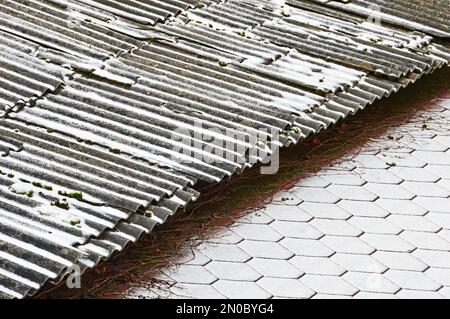 Der Rand von zwei Dächern mit verschiedenen Beschichtungen, die mit frischem Schnee bedeckt sind. Selektiver Fokus Stockfoto