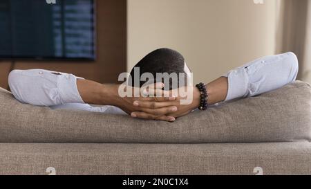 Kopf und Hände des jungen Schwarzen, der auf dem Sofa ruht Stockfoto