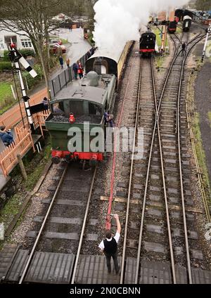 Der Feuerwehrmann des GWR-Panzers Nr. 6430 holt gleich den Einlinientempel vom Wegweiser in Buckfastleigh auf der South Devon Railway ab. Stockfoto