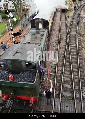 Der Feuerwehrmann des GWR-Panzers Nr. 6430 holt den Einlinientempel vom Wegweiser am Buckfastleigh-Bahnhof an der South Devon Railway ab. Stockfoto