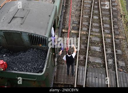 Der Feuerwehrmann des GWR-Panzers Nr. 6430 holt den Einlinientempel vom Wegweiser am Buckfastleigh-Bahnhof an der South Devon Railway ab. Stockfoto