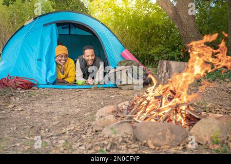 Glückliche Paare reisen und campen im Naturpark mit Zelt und Lagerfeuer. Stressfreies Entlastungskonzept. Stockfoto