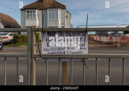Rochford, Großbritannien. Februar 2023. Handgeschriebenes Protestschild am Straßenrand in Rochford gegen Bloors große Straßenschilder. Auf dem Schild steht: „NEIN ZU BLOORS riesiges, unansehnliches 11 Ft x 5 Ft Schild direkt neben der Hauptstraße, das für Autofahrer gefährlich ist.“ Wohn- und Bauelemente sichtbar. Demonstranten von Save Holt Farm Oak Tree protestieren, um eine 100 Jahre alte Eiche zu retten. Der Baum wird voraussichtlich bis April 2023 gefällt. Penelope Barritt/Alamy Live News Stockfoto