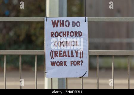 Rochford, Großbritannien. Februar 2023. Handgeschriebenes Schild mit der Aufschrift „FÜR WEN ARBEITET ROCHFORD COUNCIL ((WIRKLICH))?“ An einem Metallzaun befestigt, um die öffentliche Skepsis gegenüber den Zugehörigkeiten des Rochford Council zum Ausdruck zu bringen. Demonstranten von Save Holt Farm Oak Tree protestieren, um eine 100 Jahre alte Eiche zu retten. Der Baum wird voraussichtlich bis April 2023 gefällt. Penelope Barritt/Alamy Live News Stockfoto