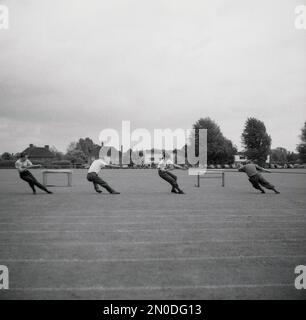 1950er Jahre, historisch, vier Männer, die an einem Tauziehen-Wettkampf draußen auf einem Grassportfeld in England, Großbritannien, teilnehmen. Stockfoto