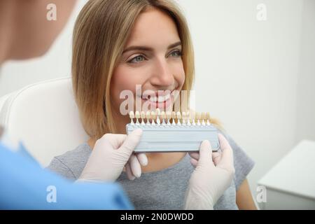 Arzt, der die Zahnfarbe des Patienten mit der Farbpalette in Klinik, Nahaufnahme abgleicht. Kosmetische Zahnheilkunde Stockfoto