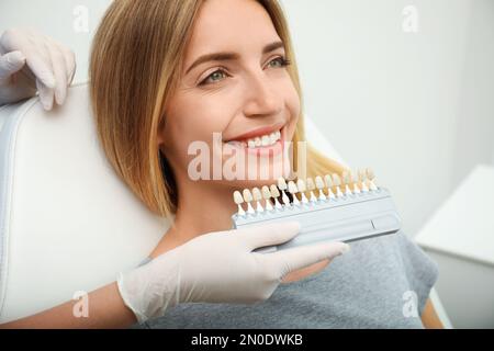 Arzt, der die Zahnfarbe des Patienten mit der Farbpalette in Klinik, Nahaufnahme abgleicht. Kosmetische Zahnheilkunde Stockfoto