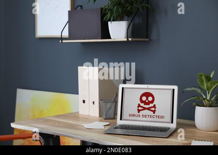 Laptop mit Warnung vor Virenangriffen auf Holztisch im Büro Stockfoto