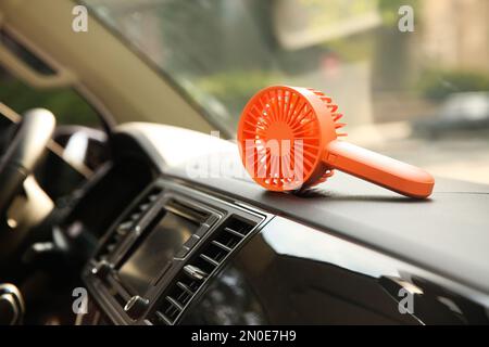 Tragbarer Ventilator auf dem Armaturenbrett im Auto. Sommerhitze Stockfoto