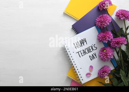 Flache Laienkomposition mit Wörtern HAPPY TEACHER'S DAY, Notizbüchern und Blumen auf weißem Holzhintergrund. Platz für Text Stockfoto