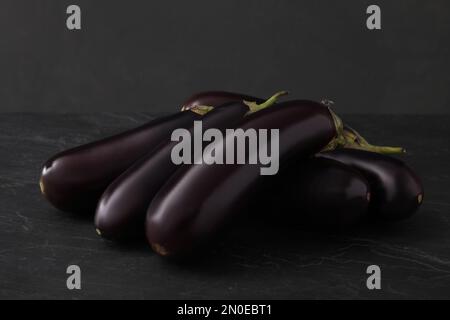 Ein Haufen roher reifer Auberginen auf einem schwarzen Tisch Stockfoto