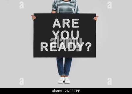 Frau mit Poster und Text: Bist du bereit? Auf hellgrauem Hintergrund, Nahaufnahme Stockfoto