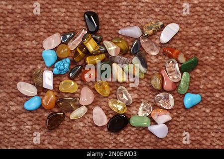 Sammlung von Halbedelsteinen auf braunem strukturiertem Brett-Hintergrund aus Nahaufnahme Stockfoto