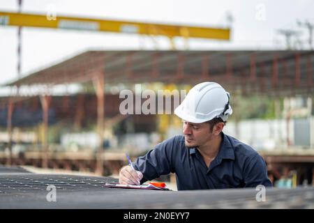 Männliche Ingenieure prüfen und kontrollieren die Arbeit der Mitarbeiter und die Qualität der hergestellten Produkte, um die Standards zu erfüllen. In der Industrie Stockfoto