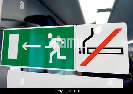Grüner Ausgang und Rauchverbotsschilder in der Nähe der Tür im Zug. Stockfoto