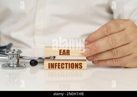 Medizinisches Konzept. Auf einer weißen Oberfläche, einem Stethoskop und Holzplatten mit der Inschrift - Ohrinfektionen Stockfoto