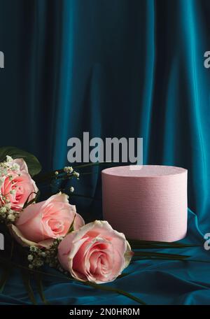 Geeignet für Produktpräsentation und Geschäftskonzept. Produktpodium und pastellrosa Blumen. Blauer Seidenvorhang. Moderne Ästhetik. Stockfoto