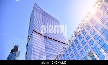 Blaue Vorhangwand aus getöntem Glas und Stahlkonstruktionen unter blauem Himmel. Ein Bruchteil eines Gebäudes. Glasfassaden an einem hellen, sonnigen Tag Stockfoto