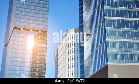 Blaue Vorhangwand aus getöntem Glas und Stahlkonstruktionen unter blauem Himmel. Ein Bruchteil eines Gebäudes. Glasfassaden an einem hellen, sonnigen Tag Stockfoto