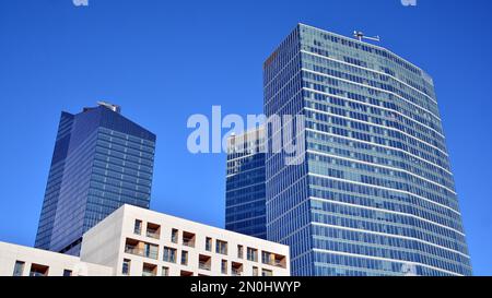 Blaue Vorhangwand aus getöntem Glas und Stahlkonstruktionen unter blauem Himmel. Ein Bruchteil eines Gebäudes. Glasfassaden an einem hellen, sonnigen Tag Stockfoto