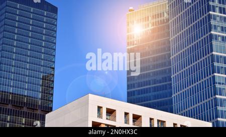 Blaue Vorhangwand aus getöntem Glas und Stahlkonstruktionen unter blauem Himmel. Ein Bruchteil eines Gebäudes. Glasfassaden an einem hellen, sonnigen Tag Stockfoto