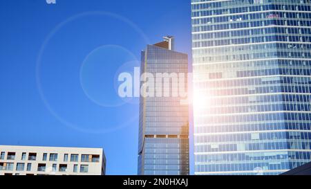 Blaue Vorhangwand aus getöntem Glas und Stahlkonstruktionen unter blauem Himmel. Ein Bruchteil eines Gebäudes. Glasfassaden an einem hellen, sonnigen Tag Stockfoto