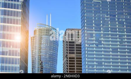 Blaue Vorhangwand aus getöntem Glas und Stahlkonstruktionen unter blauem Himmel. Ein Bruchteil eines Gebäudes. Glasfassaden an einem hellen, sonnigen Tag Stockfoto