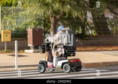 Eine Frau mit einem elektrischen Rollstuhl auf der Straße Stockfoto