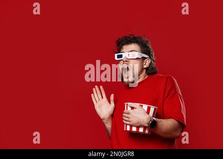 Ein verängstigter Mann mit 3D Gläsern und einem Eimer Popcorn Stockfoto