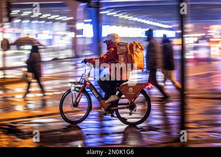 Straße am Hauptbahnhof, Lieferando Kurier, Radfahrer, Regenwetter, Stadtzentrum, Am Abend essen, NRW, Deutschland, Stockfoto