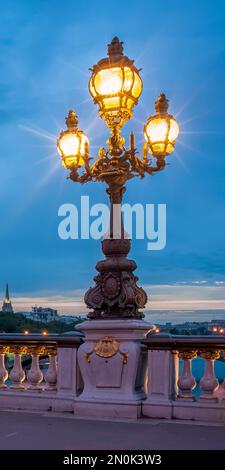 PARIS, FRANKREICH - 07. MAI 2011: Kunstvoll verzierte Kerzenleuchter auf der Pont Alexandre III leuchten nachts auf Stockfoto