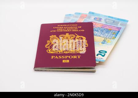 Britischer Reisepass mit Euro-Banknoten im Inneren isoliert auf weißem Hintergrund Stockfoto