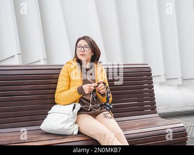 Die Frau gehäkelt draußen. Ruhige Freizeit für Frauen im städtischen Park. Anti-Stress-Hobby. Stockfoto