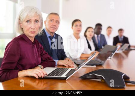 Reife, leitende, weiße Geschäftsfrau, die sich die Präsentation anhört Stockfoto