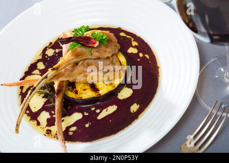 Gebackene Lammrippen in Weinsauce mit Aubergine und getrocknetem Hibiskus Stockfoto