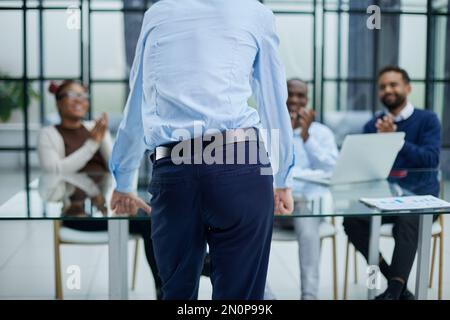 Junger Mitarbeiter, der um Rat von seinen hilfsbereiten, erfahrenen Kollegen im Büro bittet Stockfoto