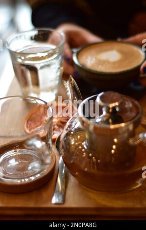 Marokkanischer Tee und Kaffee auf einem Holzteller in einem Café mit Weinscheiben und Büchern. Gemütlich. Innenraum. Stockfoto