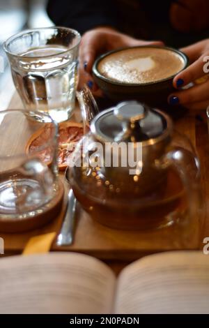 Marokkanischer Tee und Kaffee auf einem Holzteller in einem Café mit Weinscheiben und Büchern. Gemütlich. Innenraum. Stockfoto