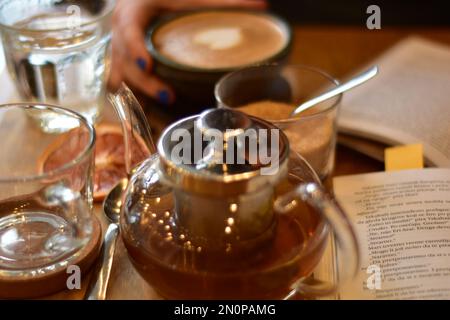 Marokkanischer Tee und Kaffee auf einem Holzteller in einem Café mit Weinscheiben und Büchern. Gemütlich. Innenraum. Stockfoto