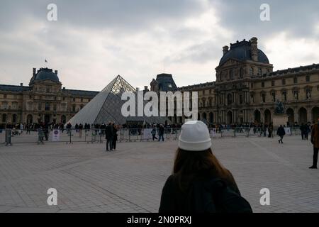 Pirâmide du Louvre. Le Louvre ist das meistbesuchte Museum der Welt, Glas-pirâmide. Besuch von Paris im Januar mit kaltem Wetter an bewölkten Tagen. Touristen. Stockfoto