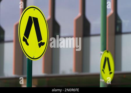 Gelbes Fußgängerschild isoliert vor einem abstrakten Gebäudehintergrund in Victoria, Australien. Stockfoto