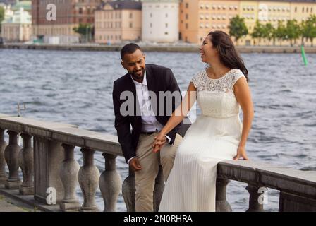 Glückliches frisch verheiratetes Paar, das am Fluss sitzt Stockfoto
