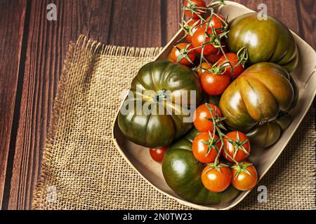 Ein wunderbarer Korb voller reifer Tomaten auf einem hellbraunen Leintuch Stockfoto