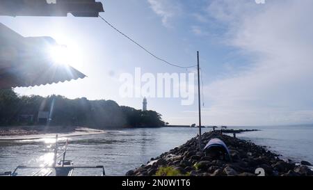 Die Felsen an der Küste werden in eine Straße zwischen dem Meer und dem Fluss, dem Hafen, dem Strand und dem Himmelblau gestapelt Stockfoto