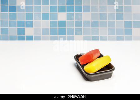 Einige rote und gelbe Glyzerin-Seifenleisten auf einem schwarzen Porzellanbehälter Stockfoto