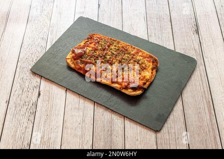 Eine kleine rechteckige Grillpizza auf einem schwarzen Schiefertablett Stockfoto