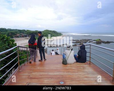 Garut, Indonesien - Dezember 12,2022: Leute, die auf der Straße oder Brücke sitzen oder sich entspannen oder Holztreppen am Strand, Blick auf den Strand Stockfoto