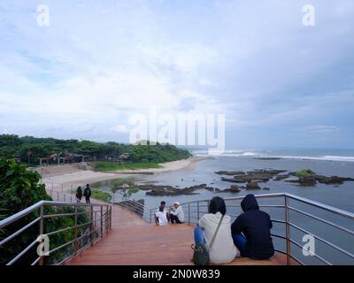 Garut, Indonesien - Dezember 12,2022: Leute, die auf der Straße oder Brücke sitzen oder sich entspannen oder Holztreppen am Strand, Blick auf den Strand Stockfoto